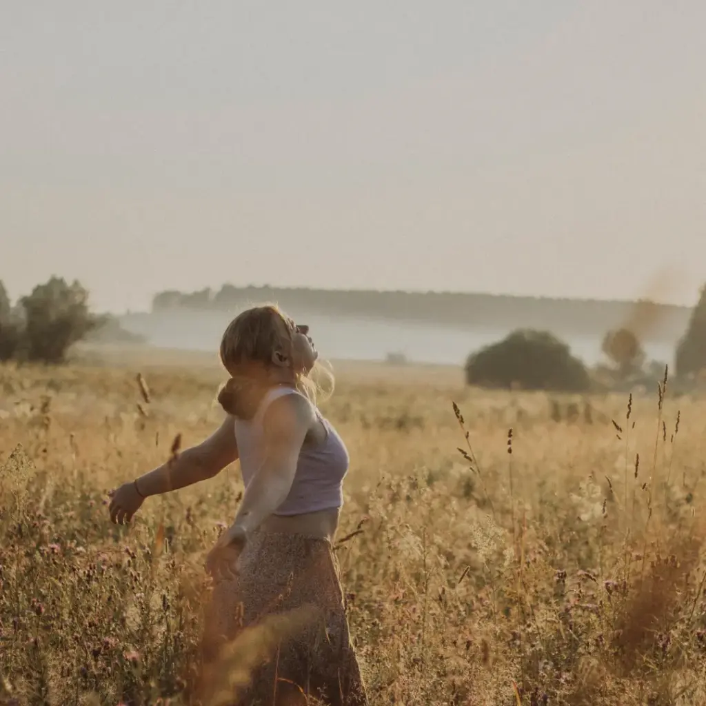 Frau steht in einer goldenen Blumenwiese – Ruhe, Naturverbundenheit und sanfte Rückkehr zu sich selbst – reCLAIM your ORIGIN